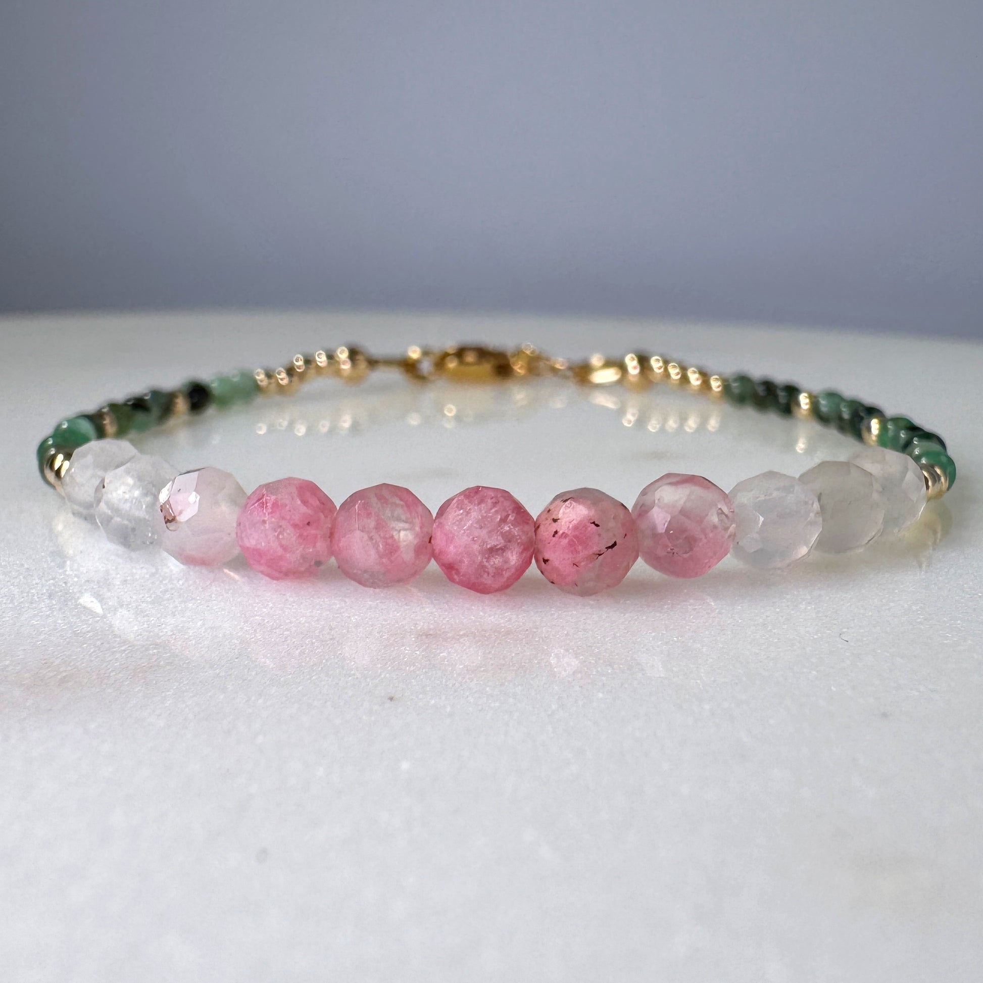 Beaded bracelet with pink, green, and clear beads on a white surface.