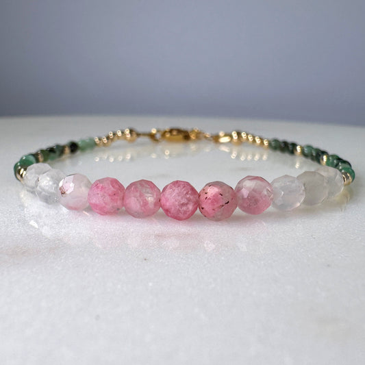 Beaded bracelet with pink, green, and clear beads on a white surface.