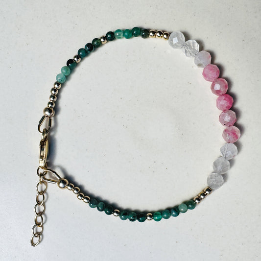 Beaded bracelet with green, pink, and gray stones on a light background