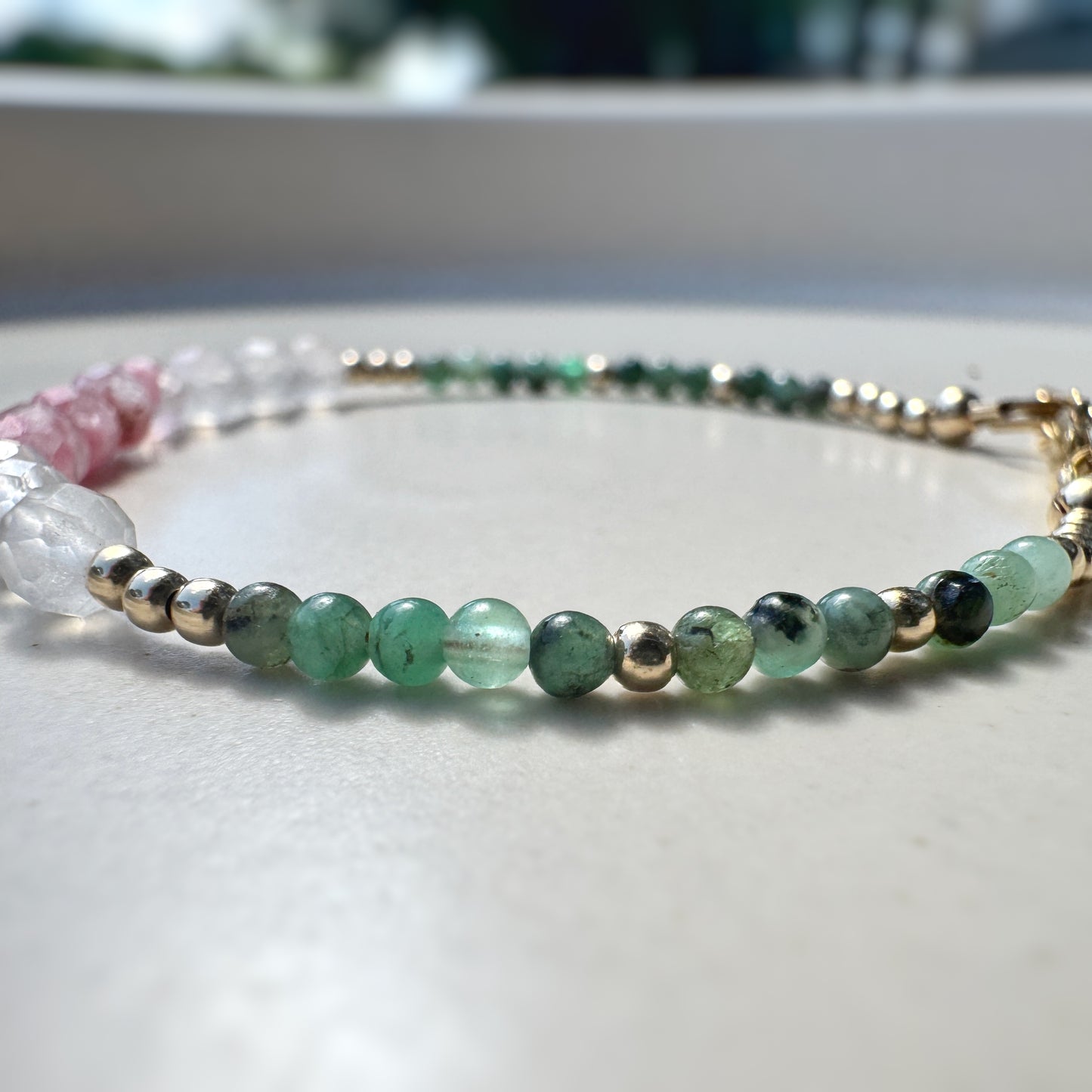 Beaded bracelet with green and gold beads on a light surface
