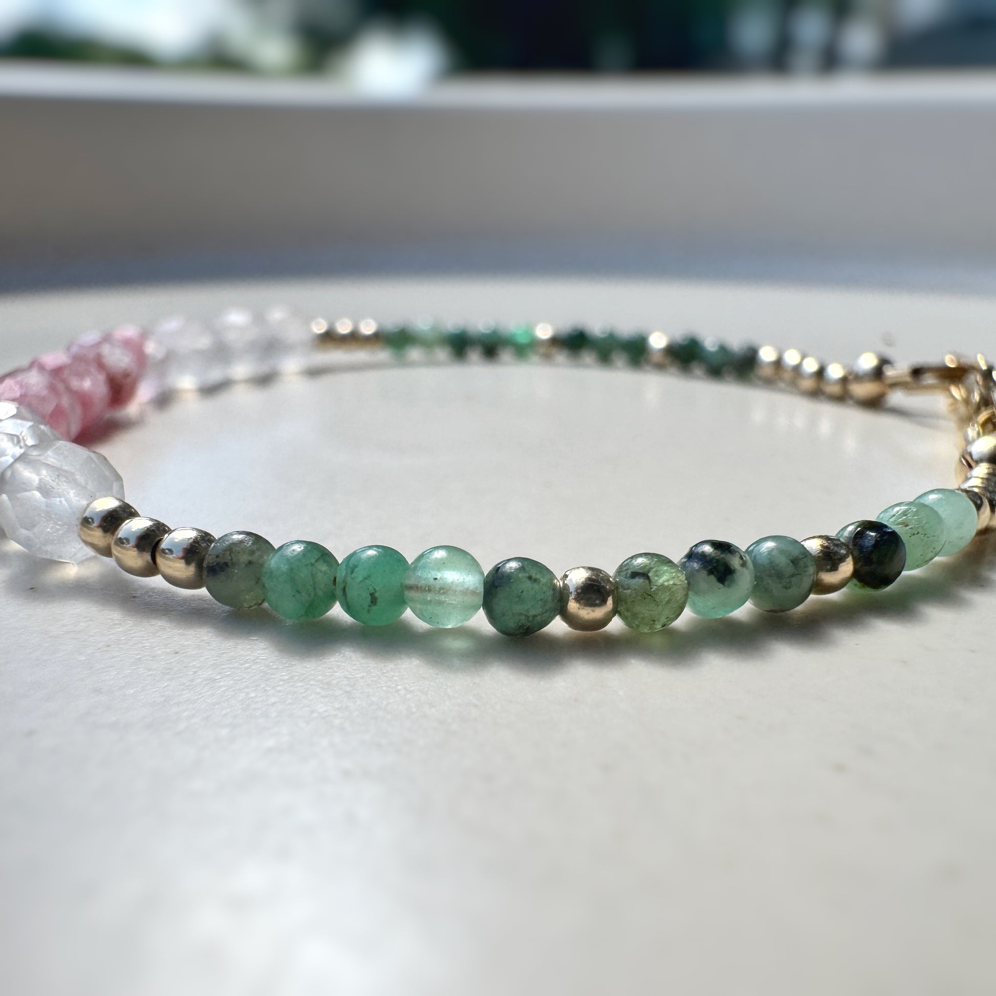 Beaded bracelet with green and gold beads on a light surface