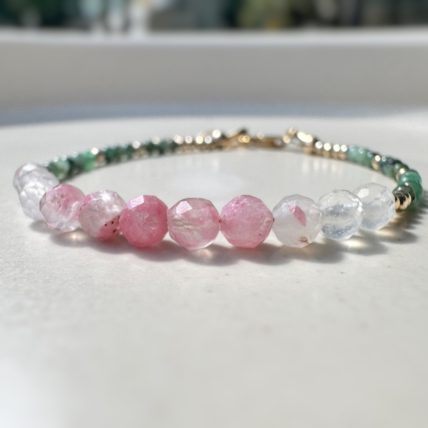 Bracelet with pink, clear, and green beads on a white surface