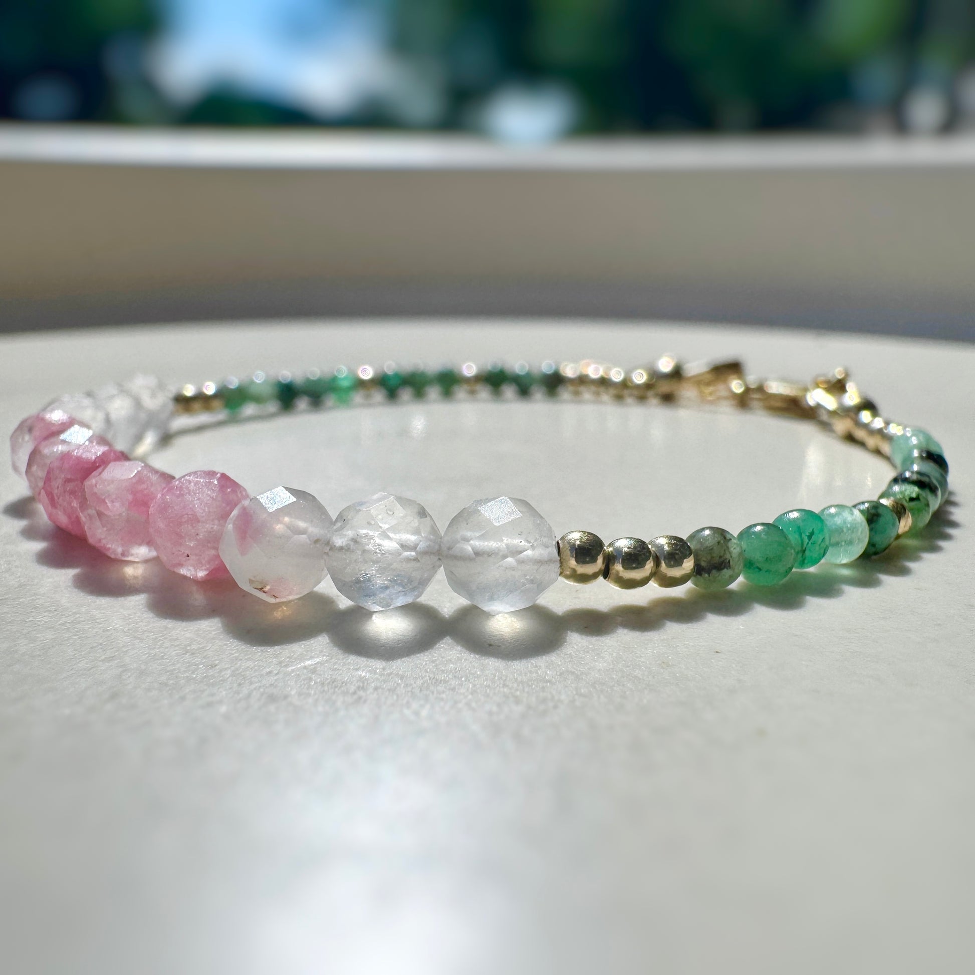 Beaded bracelet with pink, green, and clear beads on a light surface.