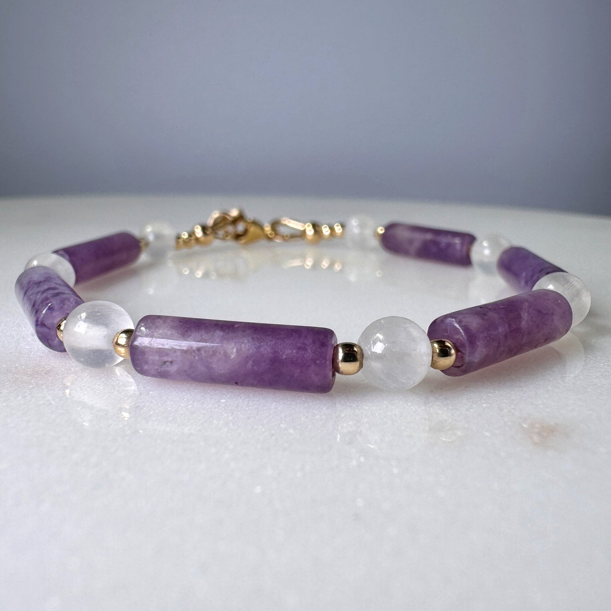 Bracelet with purple and clear beads on a light gray background